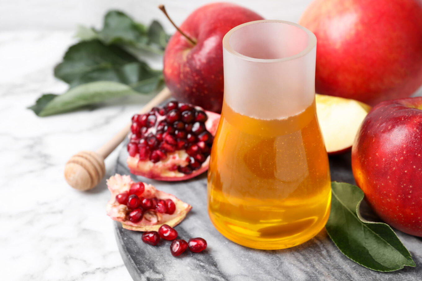 Honey, apples and pomegranate on white marble table. Rosh Hashanah holiday The High Holy Days